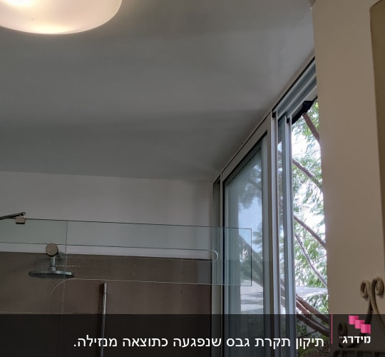 מקלחת עם ראש טוש, חלון פתוח ומדף עם מוצרים